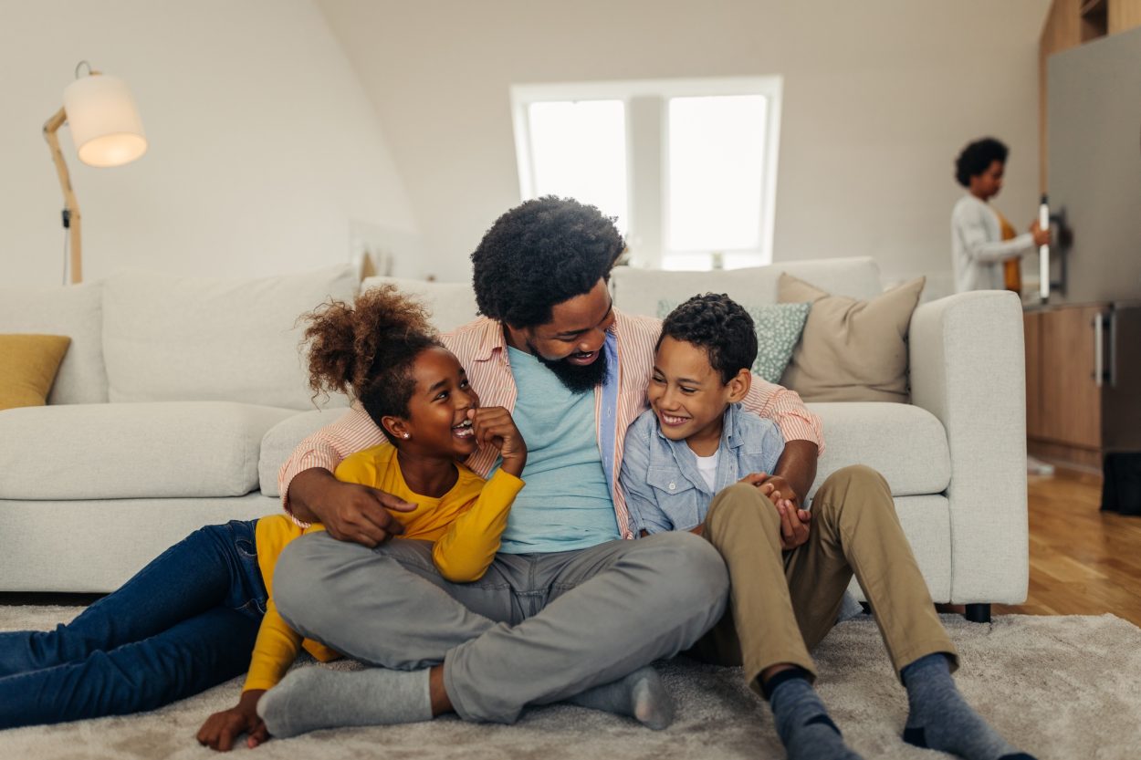 Afro family in the living room. Father tickling his children