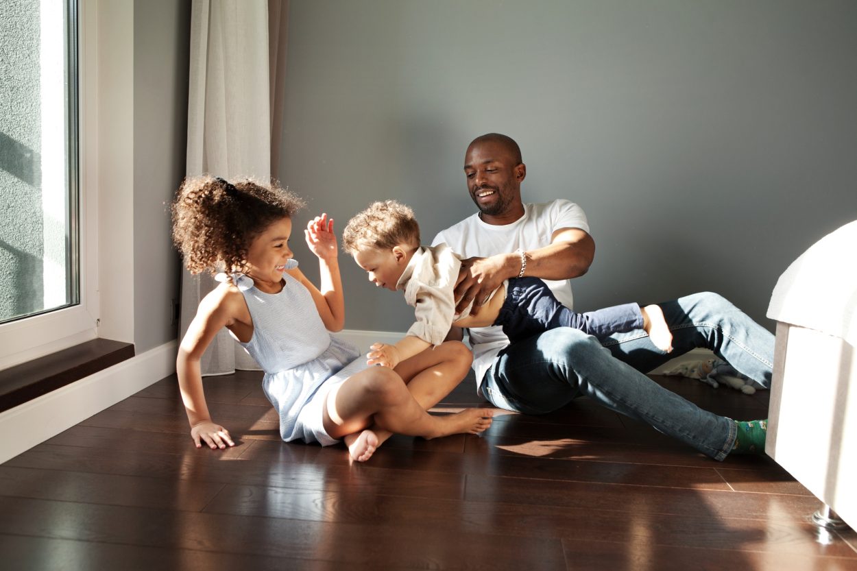 Happy Young Black Family Playing Together On Floor At Home In Living Room. Funny dad having fun with
