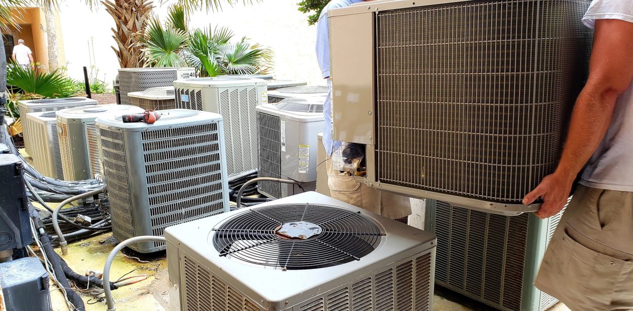 hvac technician removing old rusted broken airconditioners in HVAC at beach condo.
