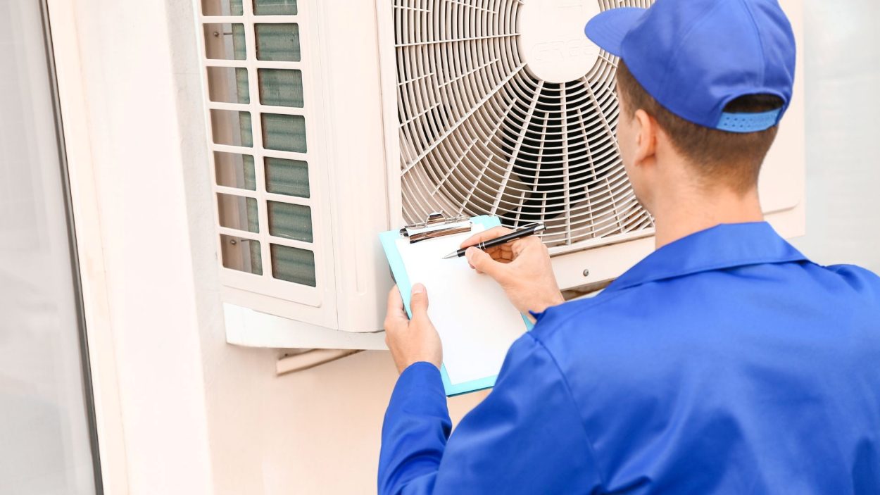 Technician inspecting AC unit for signs of needed repair in Smyrna, GA. Air conditioning service in Atlanta, GA. HVAC maintenance.