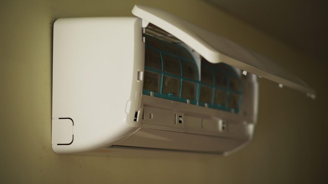 Wall-mounted AC unit with open cover, showing filter. Key factors in choosing the right AC for Atlanta homes include filter maintenance.
