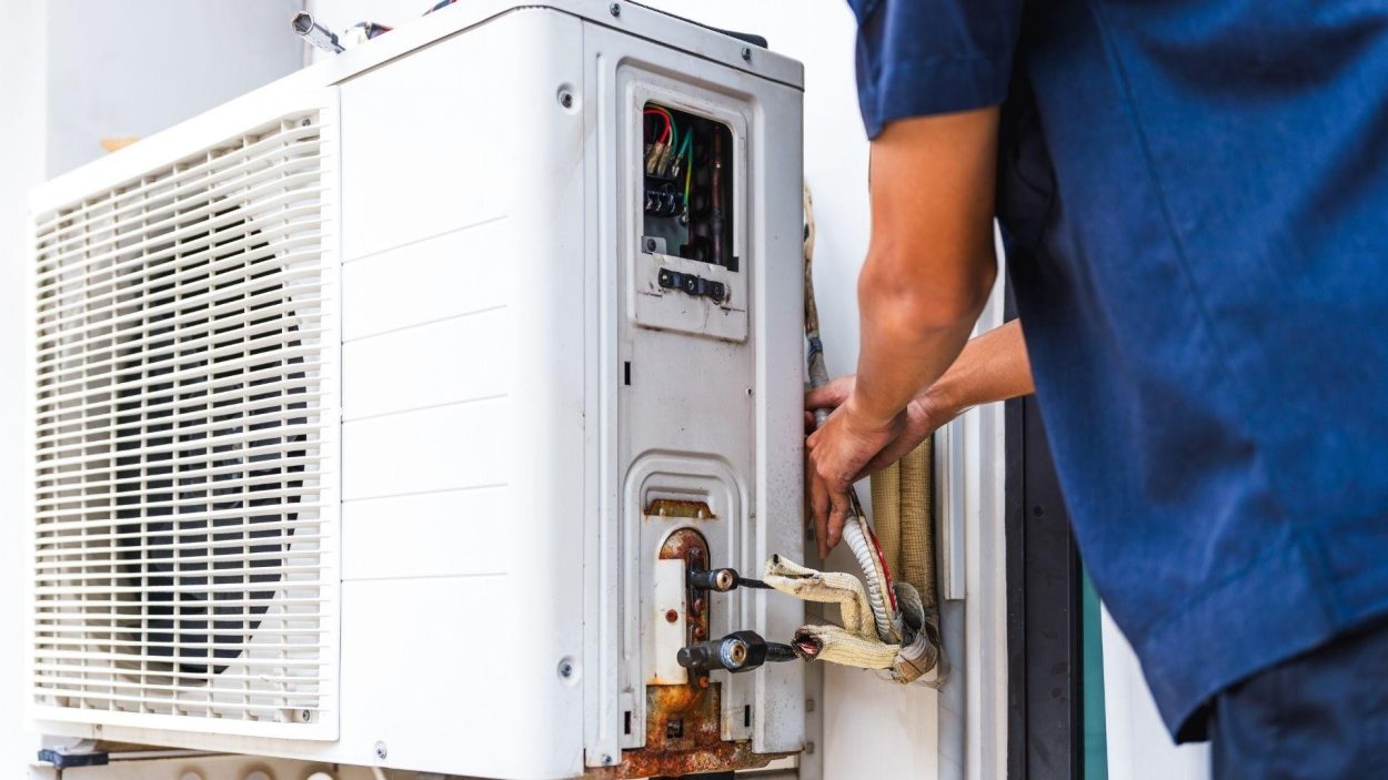 HVAC technician repairing an air conditioner. Key considerations for AC repair services include professional expertise and timely service.
