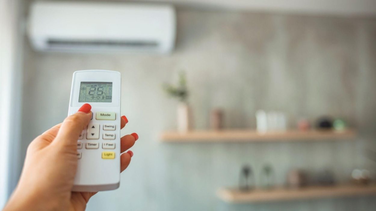 AC remote control in hand, setting temperature. For reliable AC repair services, contact us in Atlanta, GA, for affordable solutions.