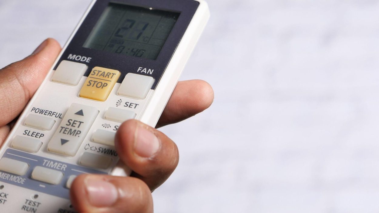 Hand holding AC remote control. Atlanta, GA residents can expect AC repair services to fix issues with their air conditioning units.