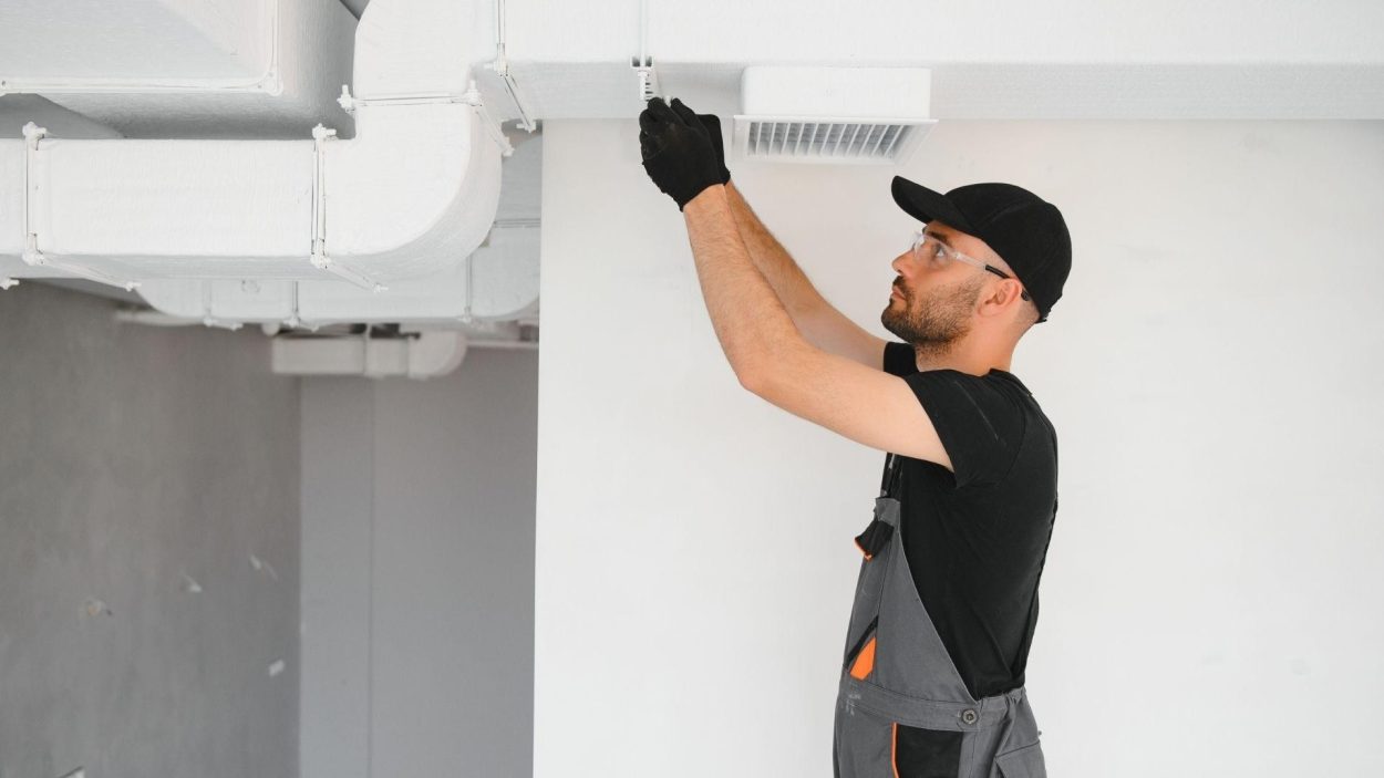 HVAC technician working on ductwork. Consider Trane models for your Atlanta, GA home's heating and cooling needs.