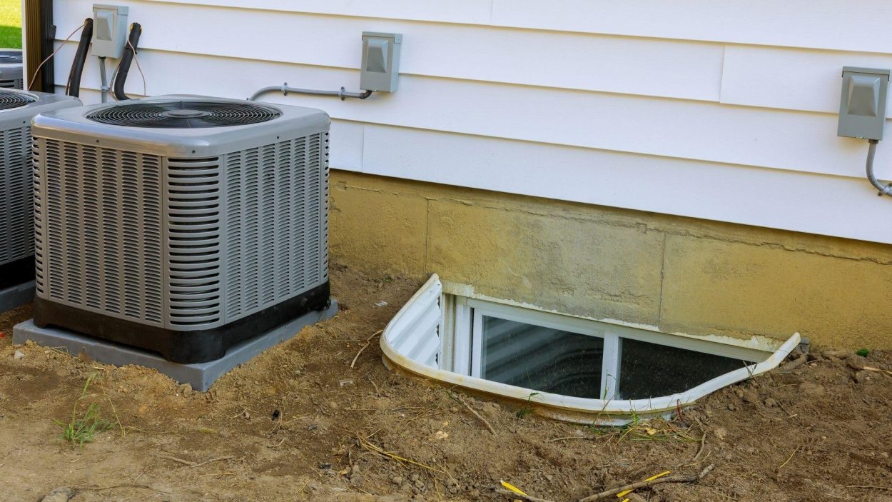Trane model air conditioner unit outside a home in Atlanta, GA, near a basement window. Find local Trane dealers for HVAC system installation.