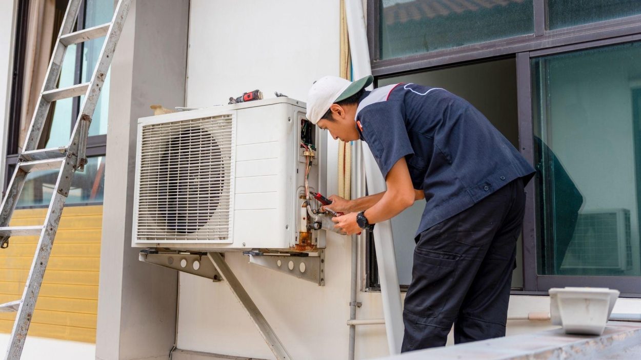 HVAC expert performs affordable AC repairs in Atlanta, GA. Technician fixing an air conditioning unit outside a building. Fast, local service.