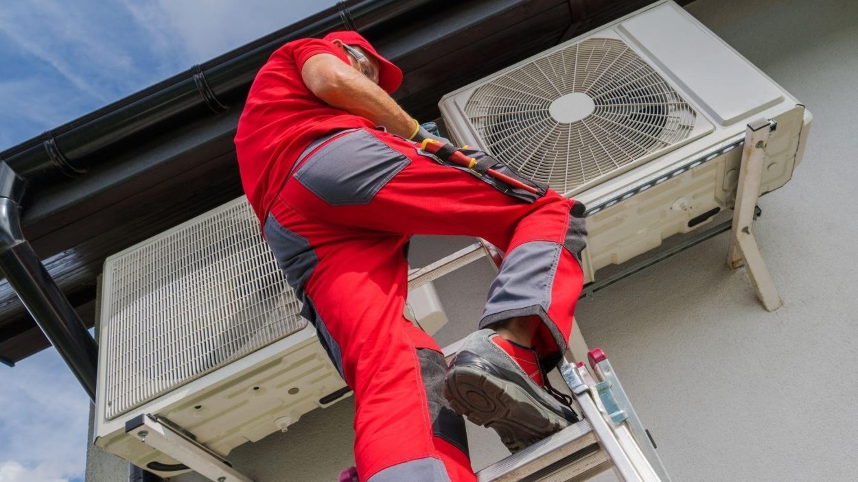 HVAC technician on ladder repairing an AC unit. Expert AC repair in Atlanta, GA for emergency service calls. Air conditioning maintenance.