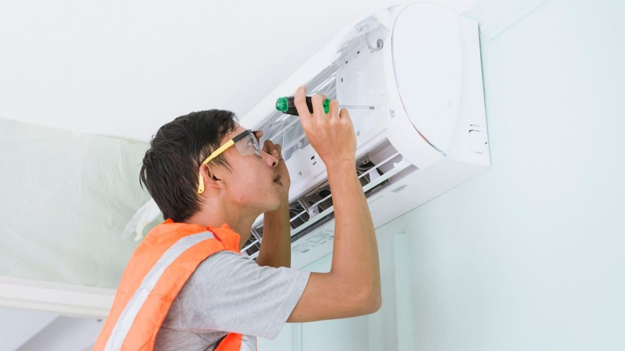 AC repair technician fixing an air conditioner. Common signs your AC needs repair in Atlanta, GA include poor cooling and strange noises.
