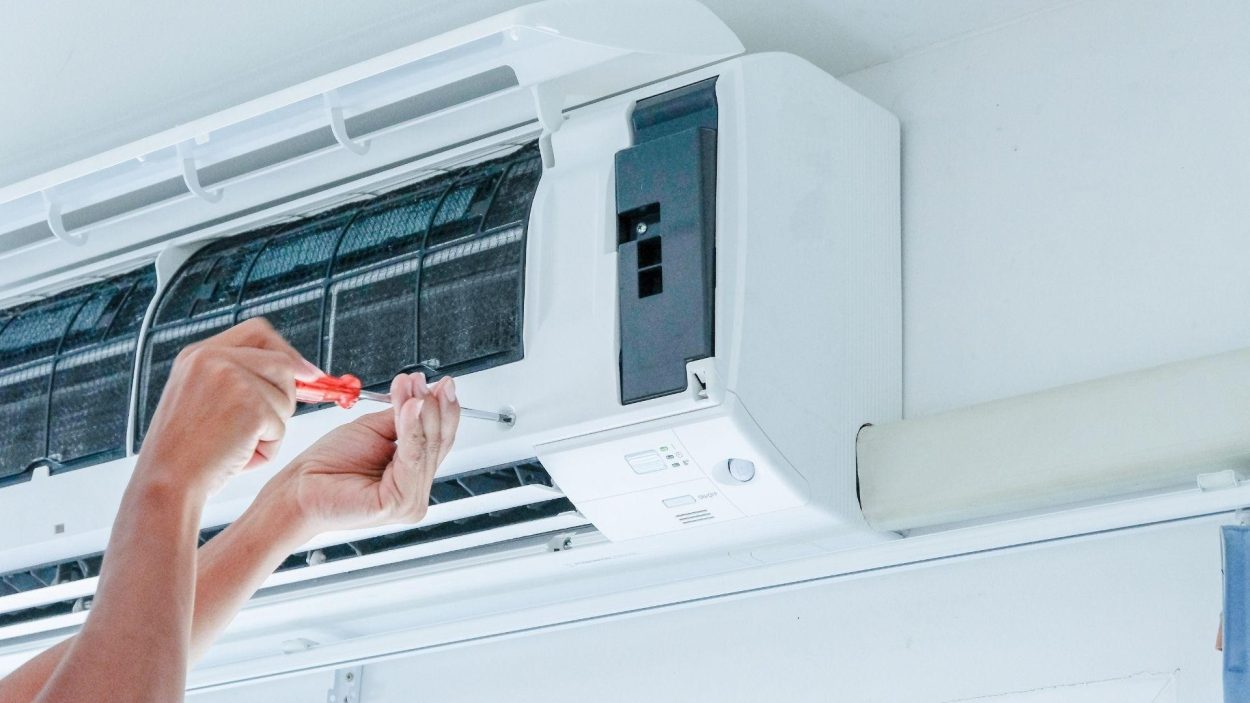 AC repair services near you: Technician using screwdriver to fix an air conditioner unit. Air conditioning maintenance in Atlanta, GA.