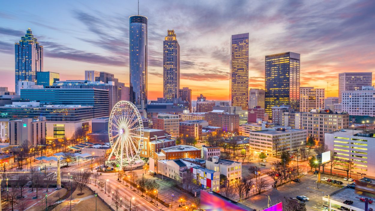 Atlanta, GA, skyline at dusk with a Ferris wheel. Consider air conditioning for your home or business to stay comfortable year-round.