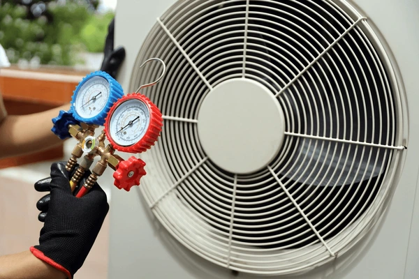 HVAC technician using pressure gauges on air conditioning unit for maintenance and repair services in Downtown Atlanta.